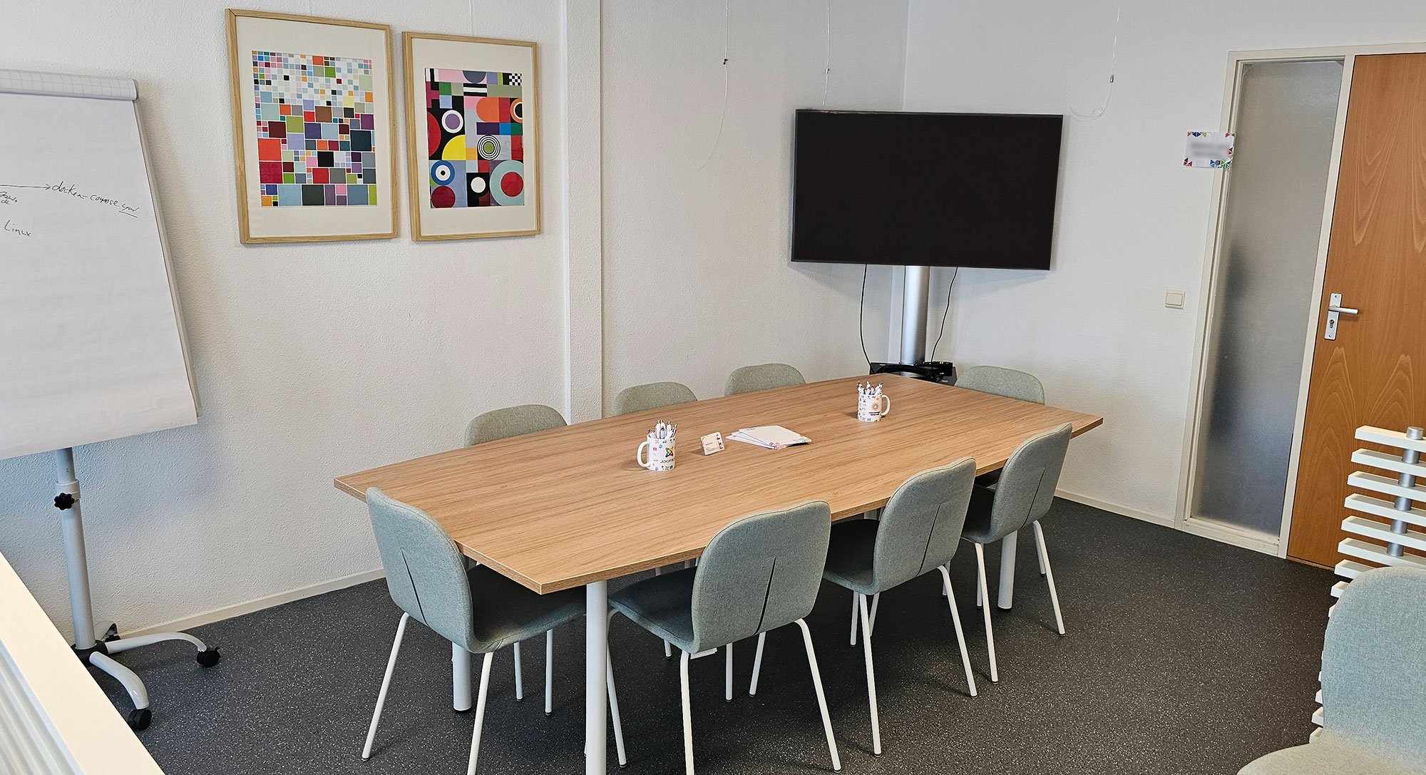 De workshop ruimte met een tafel met 8 stoelen en beeldscherm op standaard.