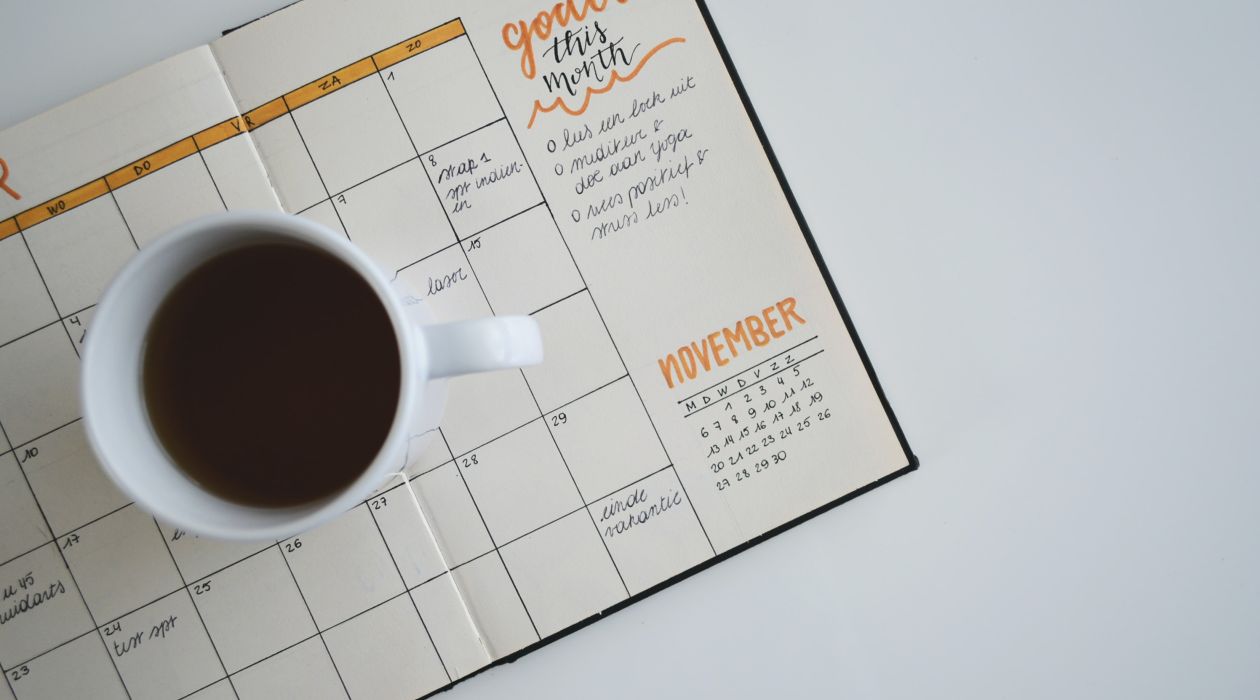 Open geslagen bullet journal maandoverzicht waar een kop koffie op staat